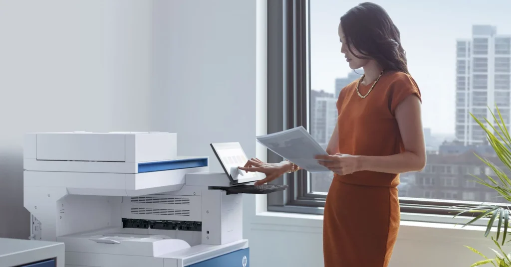 Une femme utilisant l'écran tactile d'un photocopieur HP pour imprimer des documents.