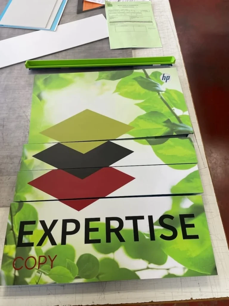 Panneaux d'habillage adhésif aux couleurs d'Expertise Copy, découpés et posés sur l'établi avant la pose
