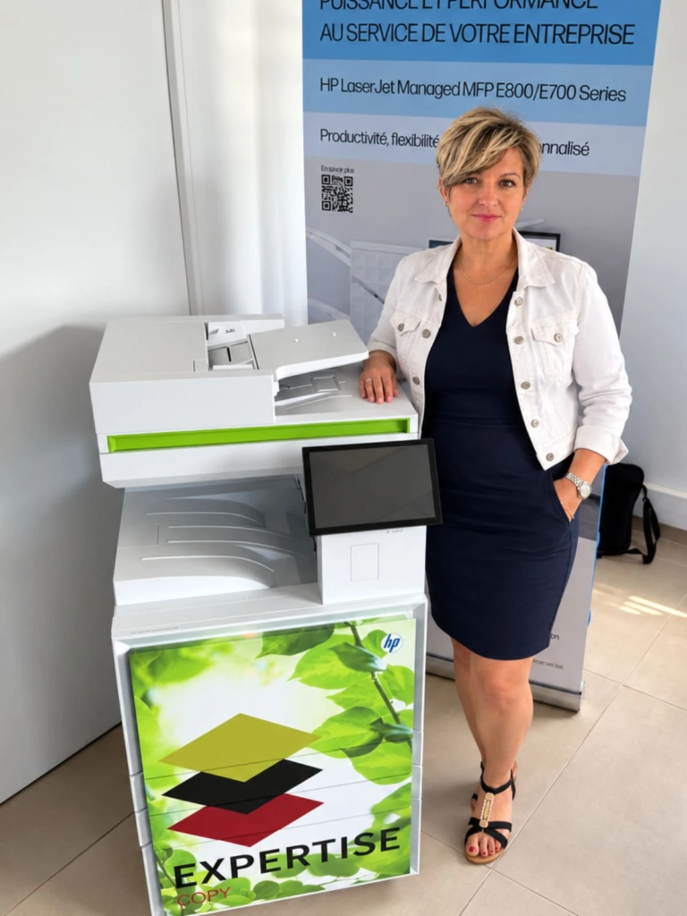 Laurence devant un photocopieur HP dont le meuble est habillé d'un visuel vert au logo Expertise Copy