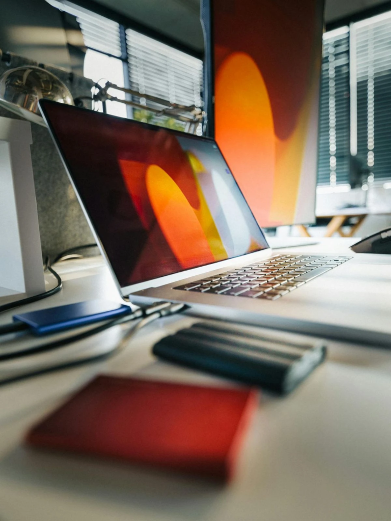 Ordinateur portable ouvert sur un bureau, relié par un câble à un disque dur externe posé à côté